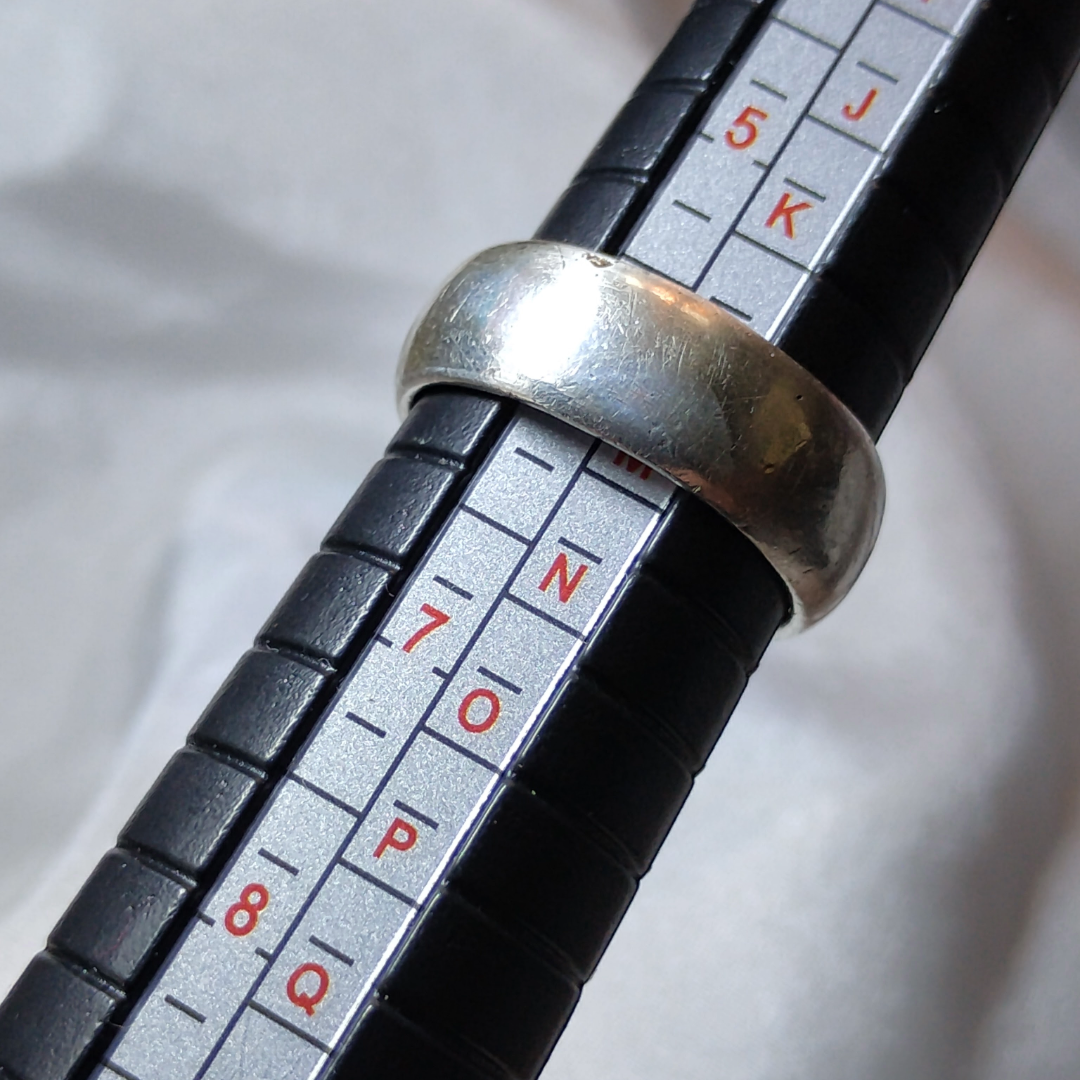 Close up shot of a vintage wide band silver ring, on a ring sizer showing size 6, from Violet Dreamer.