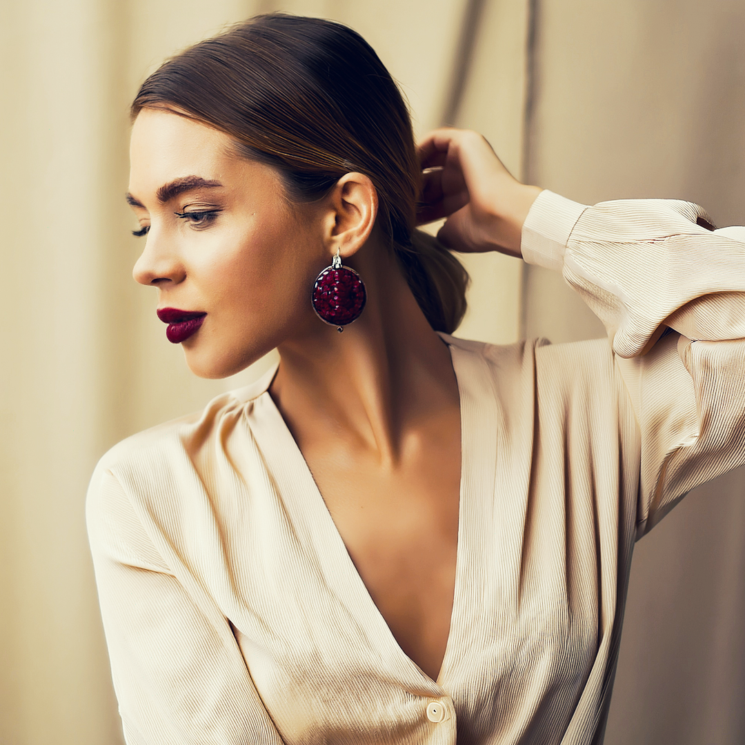A modern woman wearing a cream colored blouse and antique garnet earrings