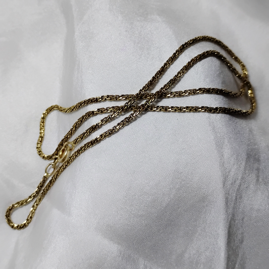 14k gold 16-inch chain displayed on a soft white fabric background, featuring a delicate and simple design with a subtle shine.