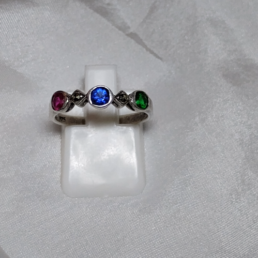 Vintage sterling silver ring featuring a trio of gemstones: a deep blue sapphire as the center stone, flanked by a vibrant red ruby and a rich green emerald, set in an elegant, timeless design.