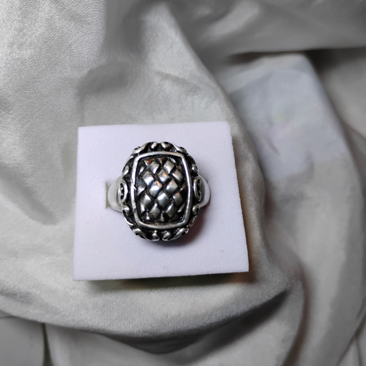 Silver ring with an ornate, raised basket-weave pattern centerpiece, framed by a decorative border.