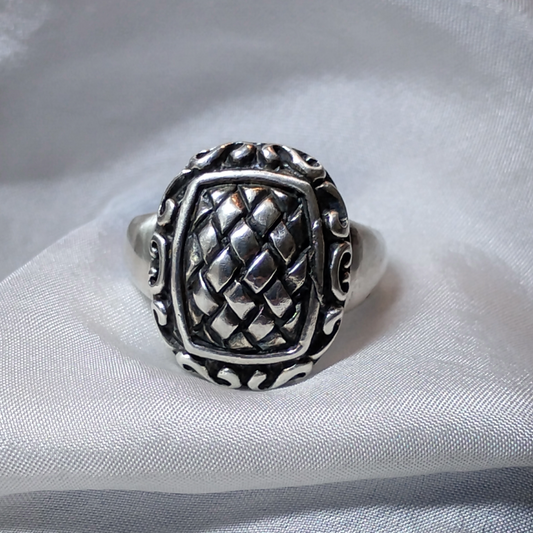 Silver ring with an ornate, raised basket-weave pattern centerpiece, framed by a decorative border.